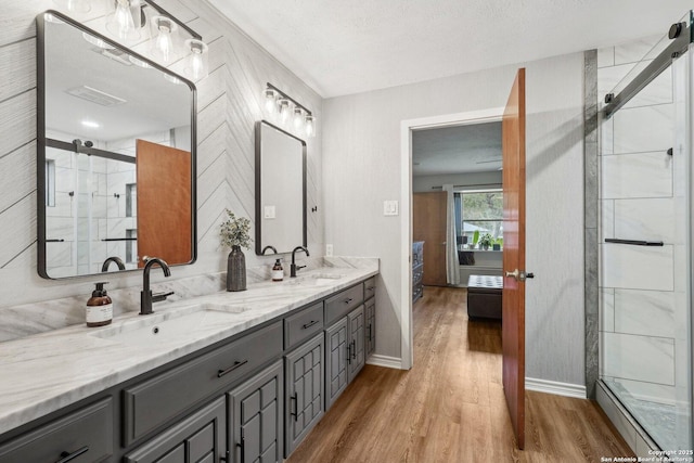 full bathroom featuring connected bathroom, wood finished floors, a stall shower, and a sink