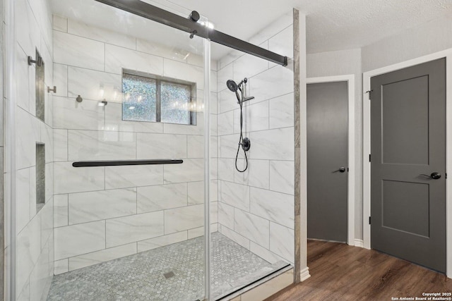 full bathroom featuring a stall shower, a textured ceiling, and wood finished floors