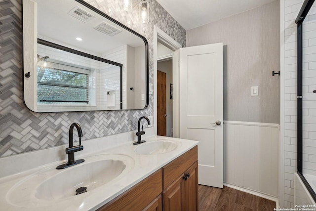 full bathroom featuring a sink, visible vents, wood finished floors, and a tile shower