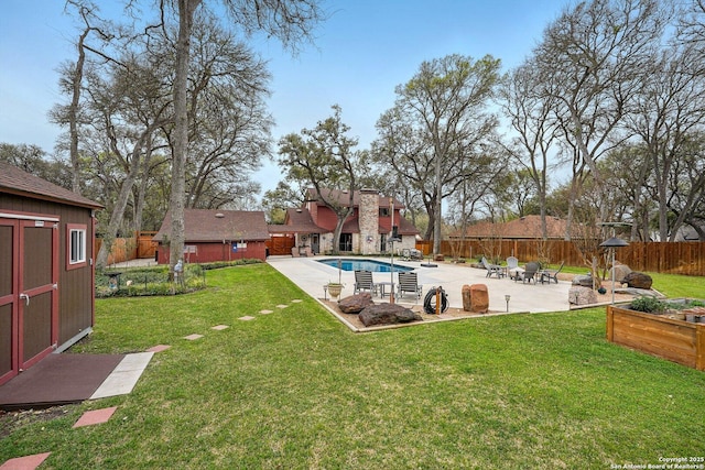 view of yard featuring a patio, a fenced in pool, a fenced backyard, an outdoor structure, and a storage unit