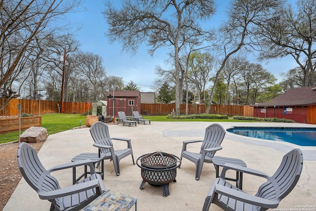 view of patio with an outbuilding, a fenced backyard, a shed, and an outdoor fire pit