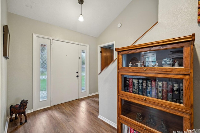 foyer featuring baseboards, lofted ceiling, and wood finished floors