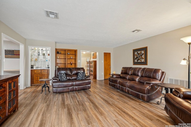 living area featuring visible vents, a textured ceiling, and light wood-type flooring