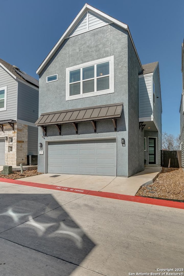 townhome / multi-family property featuring a standing seam roof, metal roof, a garage, and stucco siding