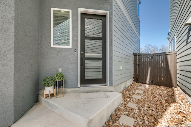 entrance to property with stucco siding and fence