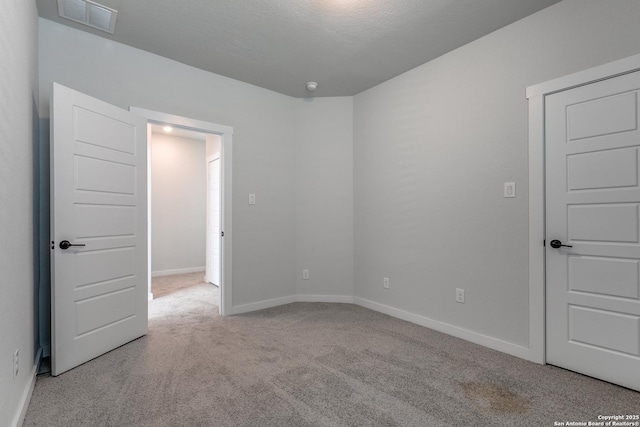 carpeted empty room with visible vents, baseboards, and a textured ceiling