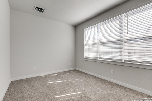 carpeted empty room featuring visible vents and baseboards