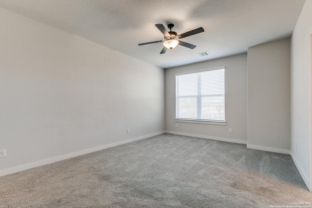 carpeted empty room featuring visible vents, a textured ceiling, baseboards, and a ceiling fan