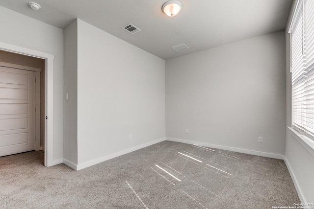 carpeted empty room with visible vents and baseboards