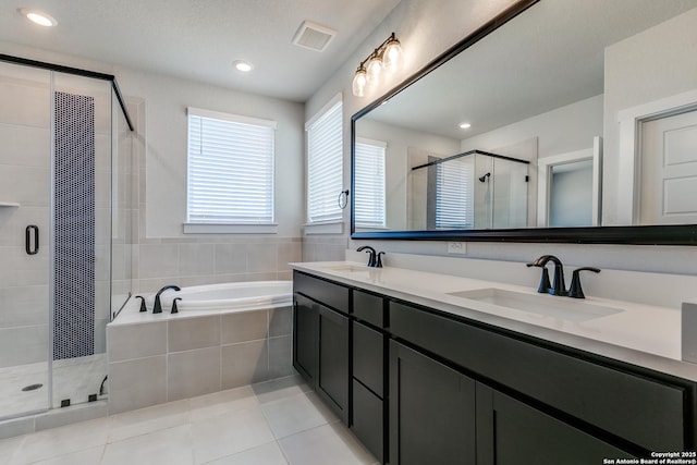 bathroom featuring a bath, tile patterned flooring, a shower stall, and a sink