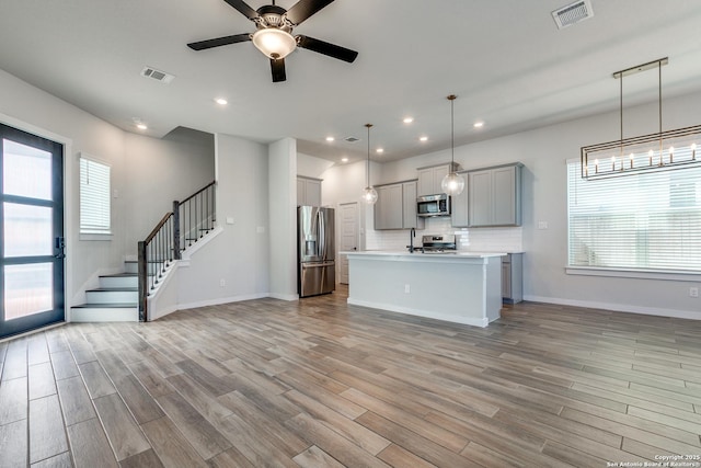 kitchen featuring visible vents, gray cabinets, stainless steel appliances, light wood-style floors, and open floor plan