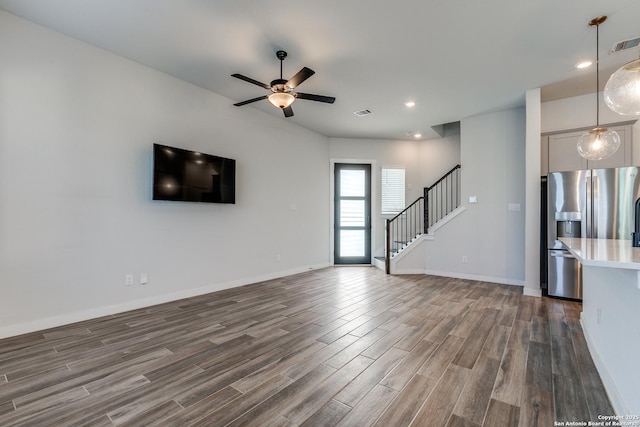 unfurnished living room with dark wood finished floors, stairway, recessed lighting, and baseboards