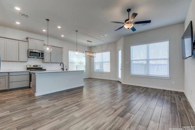 kitchen featuring visible vents, gray cabinets, appliances with stainless steel finishes, and open floor plan