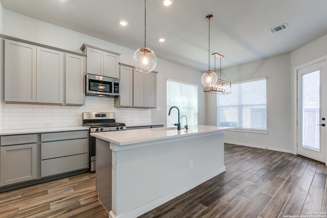 kitchen featuring visible vents, dark wood-type flooring, gray cabinets, tasteful backsplash, and appliances with stainless steel finishes