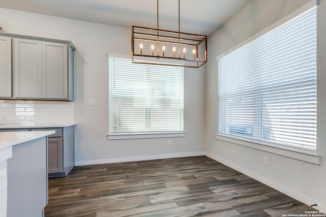 unfurnished dining area featuring dark wood-style floors and baseboards