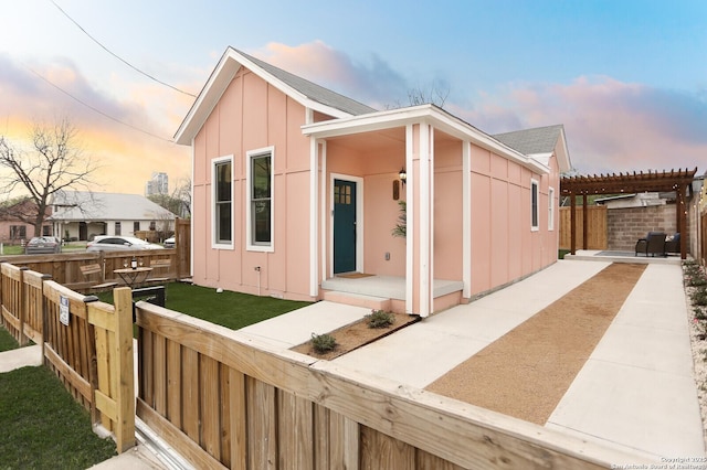 view of front of home featuring a patio area, board and batten siding, a pergola, and fence