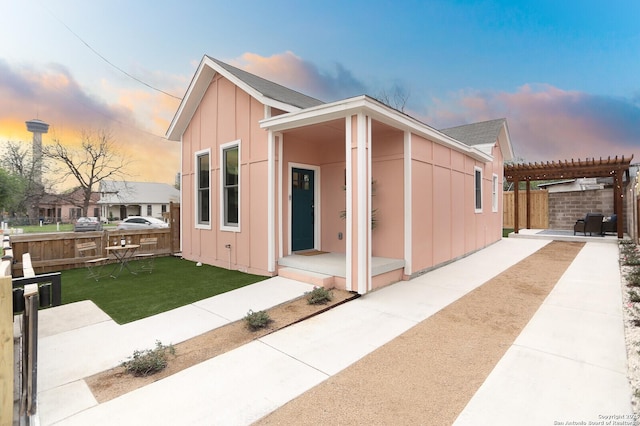 view of front facade with a lawn, a pergola, a patio, fence, and board and batten siding