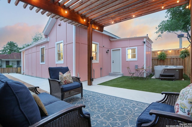 patio terrace at dusk with fence, a pergola, a hot tub, outdoor lounge area, and a lawn