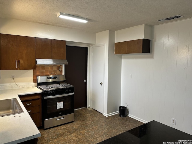 kitchen featuring visible vents, stainless steel range with gas cooktop, light countertops, dark brown cabinetry, and under cabinet range hood