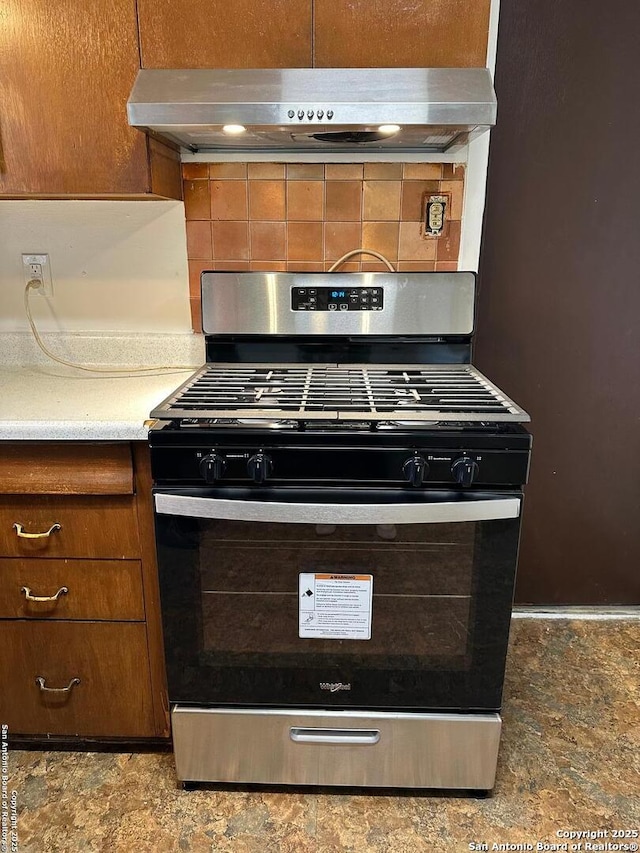 kitchen featuring under cabinet range hood, decorative backsplash, brown cabinets, and stainless steel range with gas cooktop