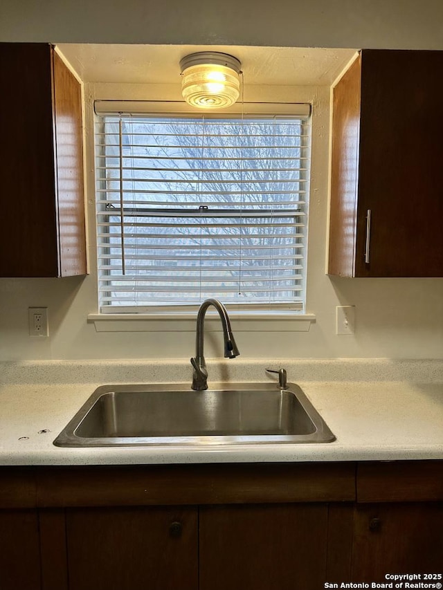 room details with light countertops, dark brown cabinets, and a sink