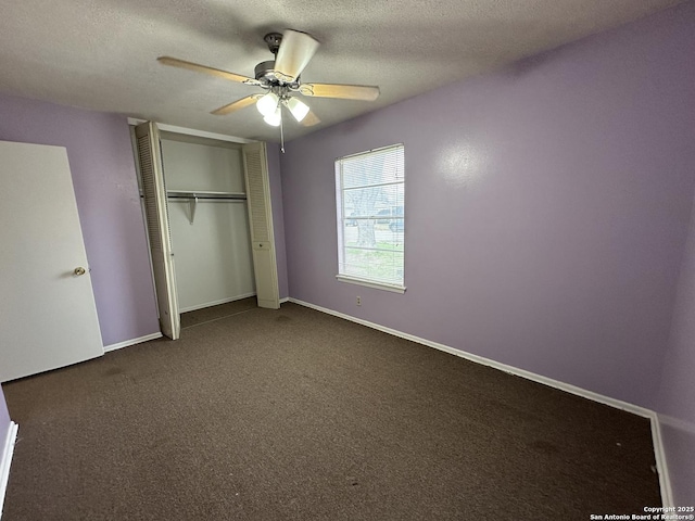 unfurnished bedroom with a closet, a textured ceiling, baseboards, and dark colored carpet