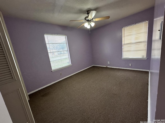 unfurnished room featuring dark colored carpet, baseboards, a textured ceiling, and ceiling fan