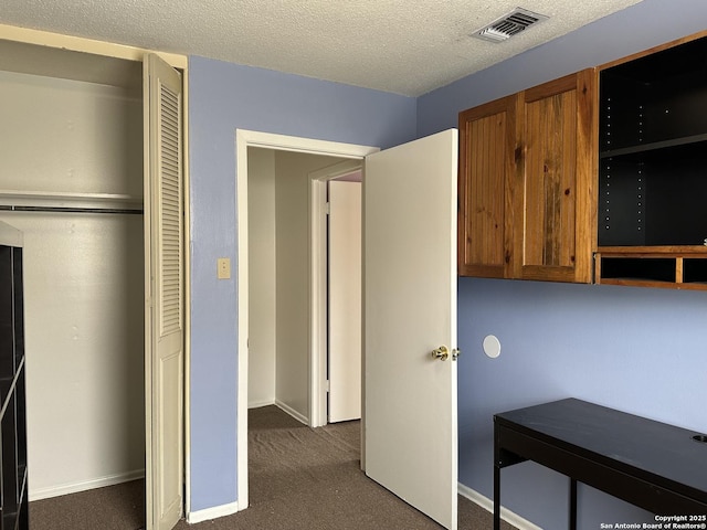 interior space with baseboards, visible vents, dark colored carpet, and a textured ceiling