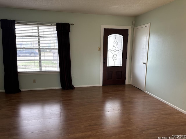 foyer featuring a textured ceiling, baseboards, and wood finished floors