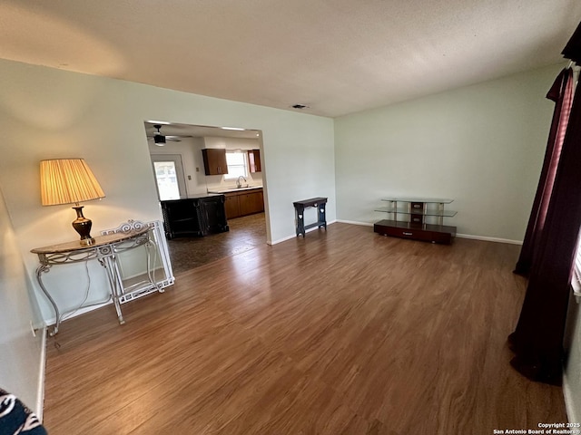 unfurnished living room featuring dark wood-type flooring, visible vents, baseboards, and ceiling fan