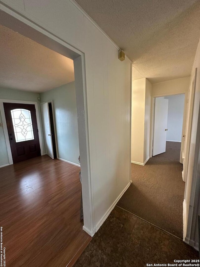 hall featuring wood finished floors, baseboards, and a textured ceiling