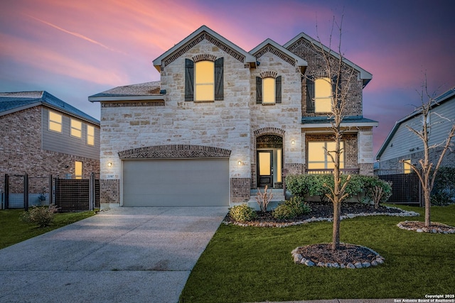 french country home with a lawn, driveway, stone siding, fence, and a garage
