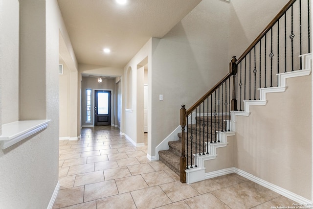 foyer entrance featuring light tile patterned floors, stairway, visible vents, and baseboards