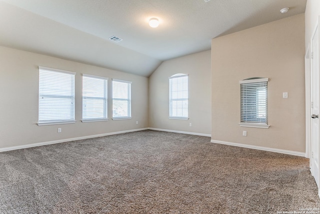 unfurnished room with visible vents, lofted ceiling, carpet, and baseboards