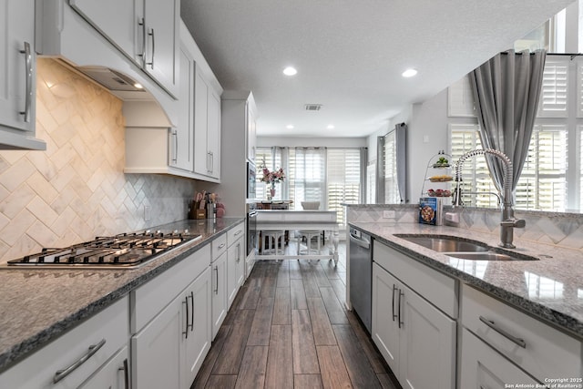 kitchen with visible vents, a sink, dark wood-style floors, appliances with stainless steel finishes, and light stone countertops