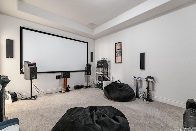 carpeted home theater room featuring a tray ceiling, baseboards, and visible vents