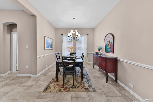 dining room featuring arched walkways, a notable chandelier, and baseboards