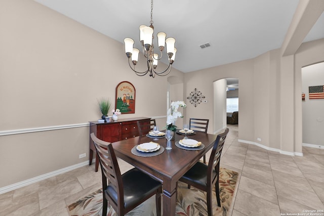 dining area featuring baseboards, arched walkways, a notable chandelier, and visible vents