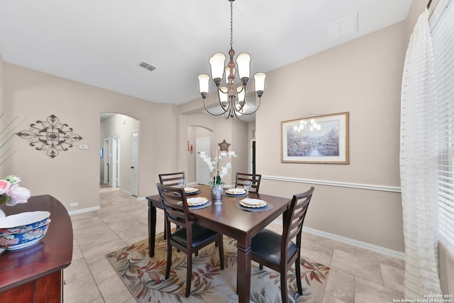 dining space featuring visible vents, arched walkways, a notable chandelier, and baseboards