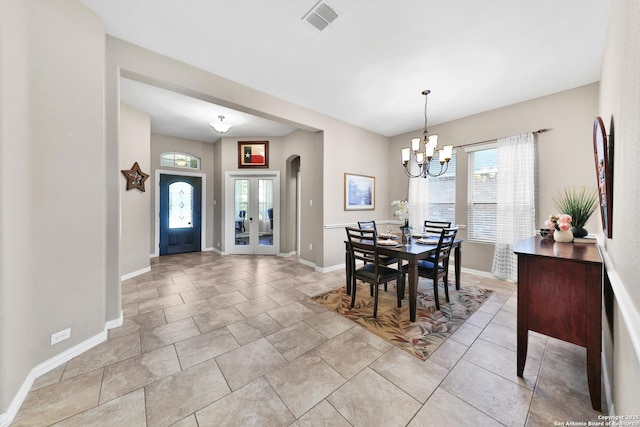 dining space featuring arched walkways, visible vents, baseboards, and an inviting chandelier