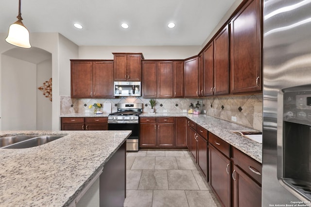 kitchen with light stone countertops, decorative light fixtures, decorative backsplash, recessed lighting, and stainless steel appliances