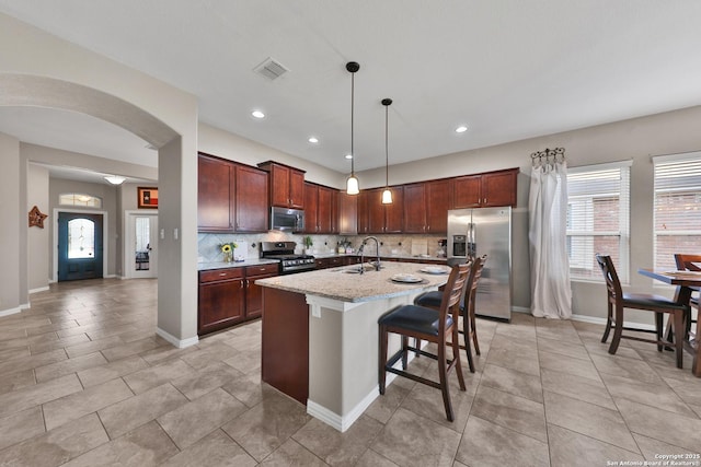 kitchen featuring visible vents, backsplash, a breakfast bar area, stainless steel appliances, and a sink