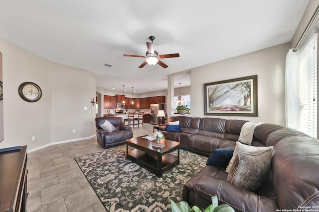 living area featuring baseboards, visible vents, a wealth of natural light, and ceiling fan