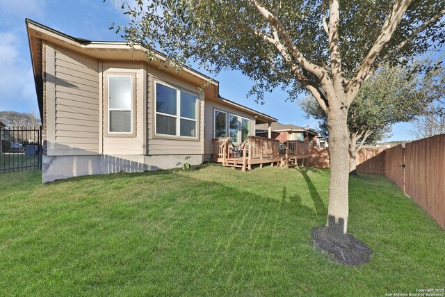 rear view of property featuring a deck, a fenced backyard, and a lawn