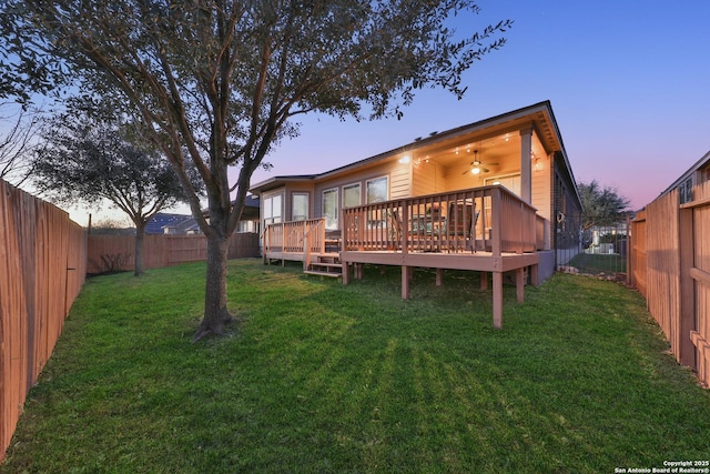 back of property featuring a yard, a wooden deck, and a fenced backyard