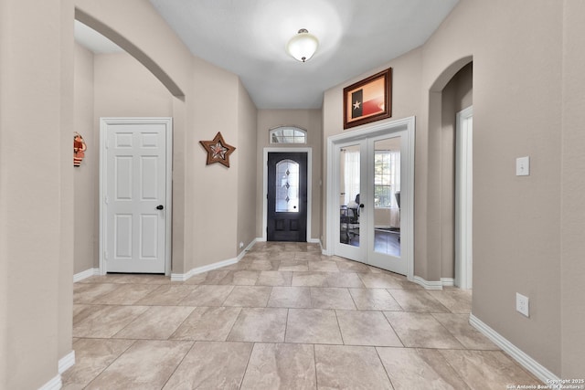 entryway with arched walkways, french doors, and baseboards