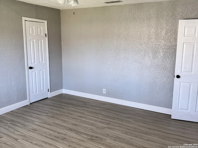 unfurnished room featuring ceiling fan, visible vents, baseboards, and wood finished floors