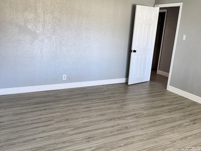 spare room with baseboards and wood finished floors