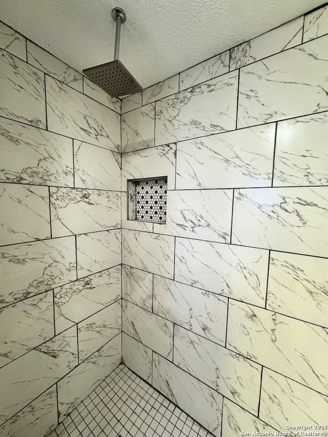 bathroom with a tile shower and a textured ceiling