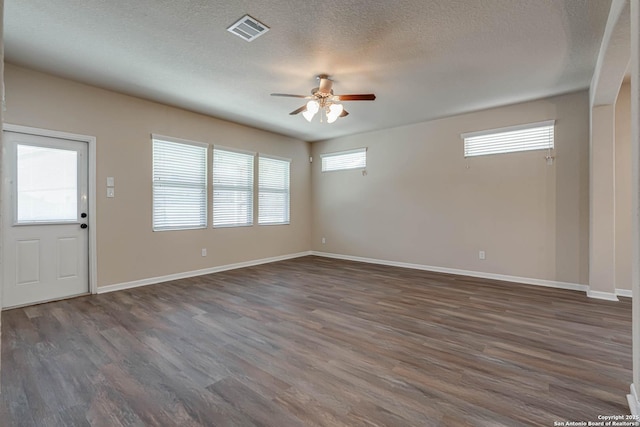 interior space featuring wood finished floors, baseboards, a ceiling fan, visible vents, and a textured ceiling